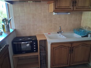 A kitchen with a built-in microwave, a sink, and wooden cabinets. - Quiet 4-person vacation rental in the countryside, with amenities just a 5-minute walk away, a pool, and more (Maubec)