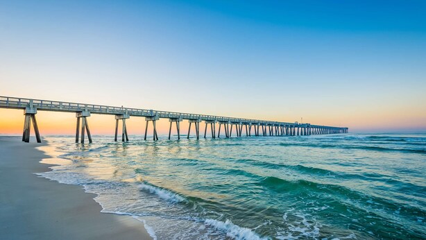 A pier extending into the ocean with waves gently lapping at the shore.