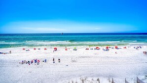 A beach with people, umbrellas, and beach chairs. - Gorgeous Gulf-front condo - step onto the beach from your private balcony (Santa Rosa Beach)