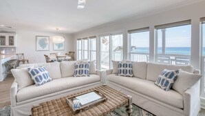 A spacious living room with two beige sofas, a coffee table, and a ceiling fan. Large windows offer a view of the ocean. - Gorgeous Gulf-front condo - step onto the beach from your private balcony (Santa Rosa Beach)