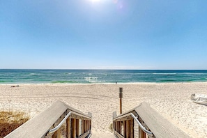 A beach view with wooden deck chairs and a sandy beach. - Inviting condo near the beach with patio, tennis, pool, & W&D (Navarre Beach)
