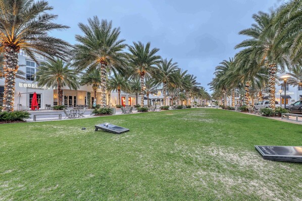 A hotel courtyard with palm trees, outdoor seating, and a well-maintained lawn. - Convenient studio w/shared pool and great location moments away from the beach (Seacrest)