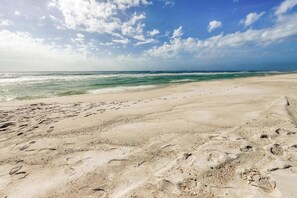 A sandy beach with footprints and a clear view of the ocean under a partly cloudy sky. - Convenient studio w/shared pool and great location moments away from the beach (Seacrest)