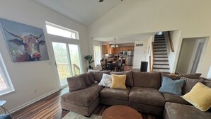A spacious living room with a sectional sofa, a round coffee table, and a large painting on the wall.