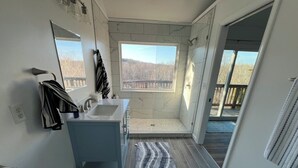 A modern bathroom with a large window, a shower, and a sink.