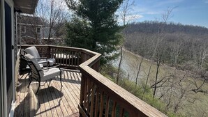 A wooden deck with a chair, a view of a forested area, and a clear sky.