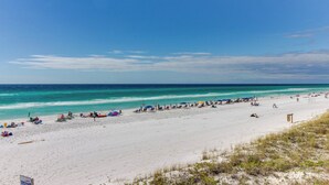 Une plage de sable blanc, avec une eau turquoise cristalline et un ciel bleu azur.