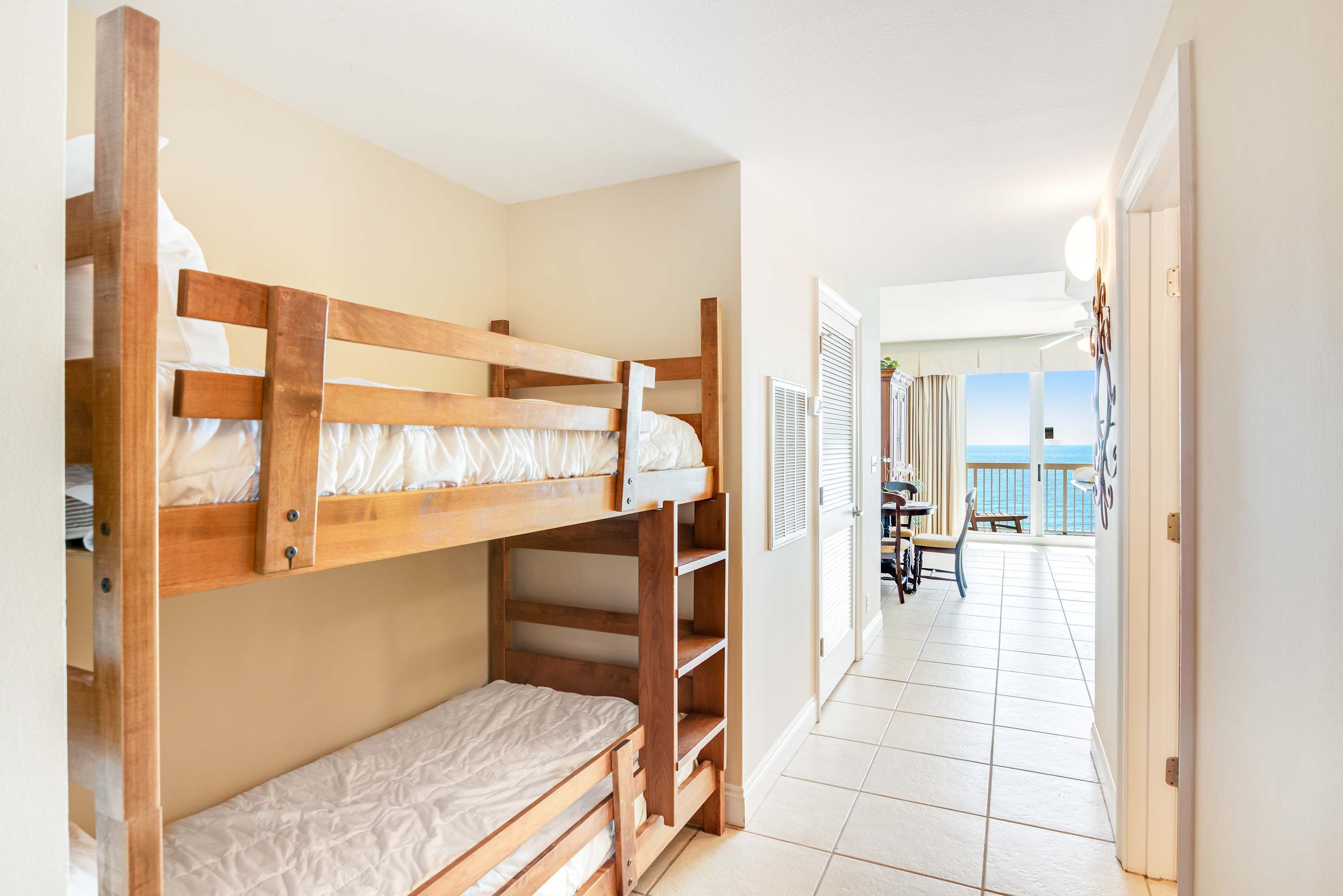 A room with bunk beds, a balcony with a view, and a dining area with a table and chairs.