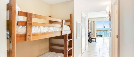 A room with bunk beds, a balcony with a view, and a dining area with a table and chairs.