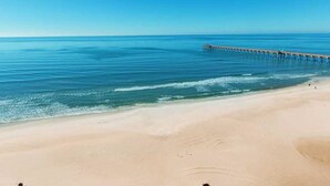 En strand med en træbro, der strækker sig ud i havet.