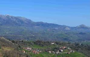 Eine gebirgige Landschaft mit verstreuten Häusern und blauem Himmel.