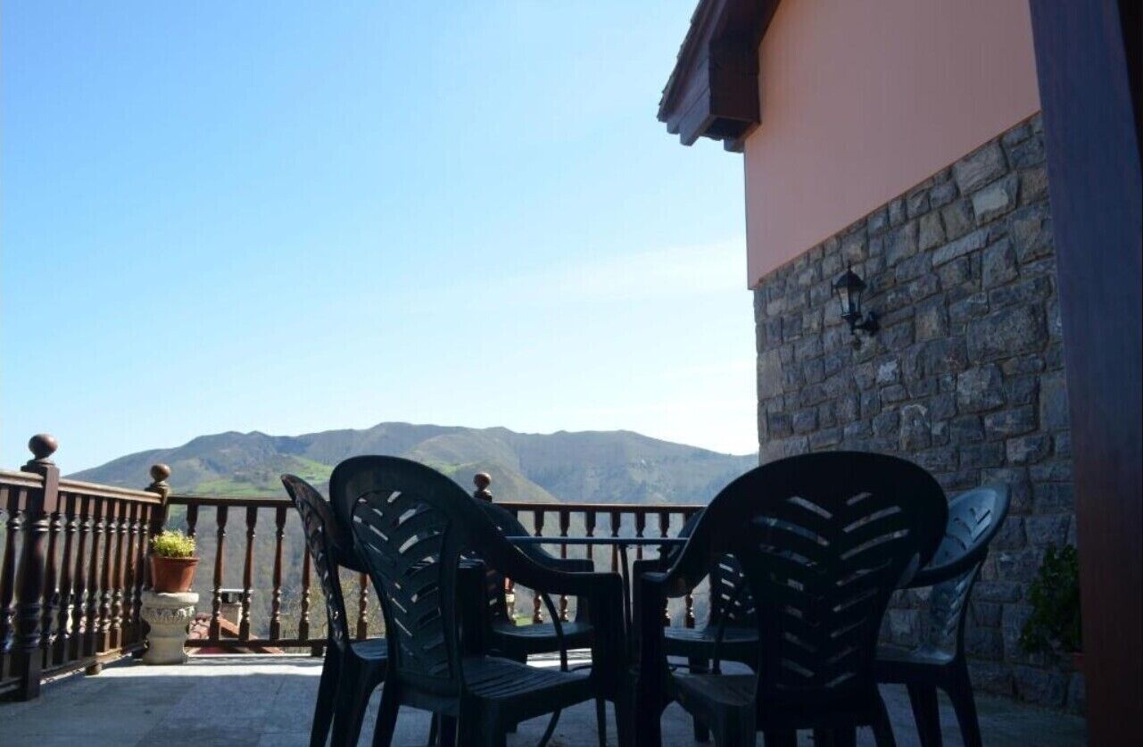 Un balcon avec une table et des chaises, donnant sur un paysage montagneux.