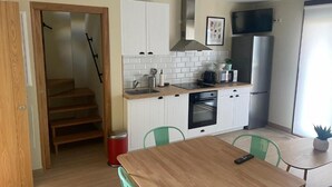 Una cocina moderna con armarios blancos, una mesa de madera y sillas verdes.