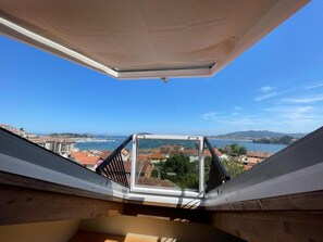 A view from a high vantage point, likely a balcony or terrace, overlooking a coastal town with buildings and a body of water. - Duplex with a communal pool, Ribeira (Baiona)