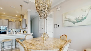 Un espace repas comprenant une table en marbre, des chaises et un lustre.