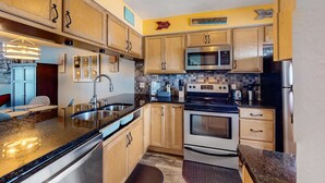 Una cucina con mobili in legno, lavello in acciaio inossidabile, forno a microonde, forno e frigorifero.