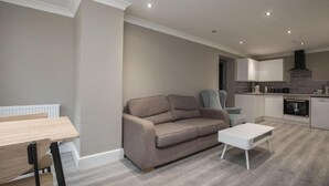 A modern kitchen with white cabinets, a built-in oven, and a black range hood. - Charming 2-bedroom Apartment in Central Kingston Upon Thames (Kingston Upon Thames)