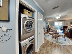 A laundry room with stacked washers and dryers, a dining area with a round table and chairs, and a ceiling fan.