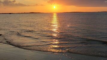 A sunset over a calm sea with a boat in the distance.
