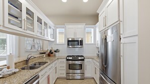 Una cocina moderna con armarios blancos, electrodomésticos de acero inoxidable y encimera de granito.