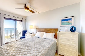 Un dormitorio con cama, cómoda, mesita de noche, silla, ventilador de techo y vista a la playa.