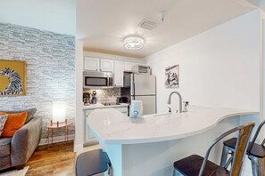 A modern kitchen with white cabinets, a large island with a sink, and stainless steel appliances. - Lakefront resort condo with heated outdoor pool, hot tub, balcony, lake views (Panama City Beach)