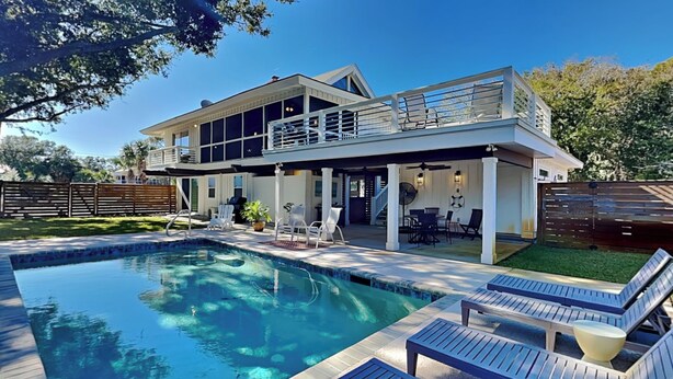 Ett modernt hus med en swimmingpool, utemöbler och en täckt uteplats.