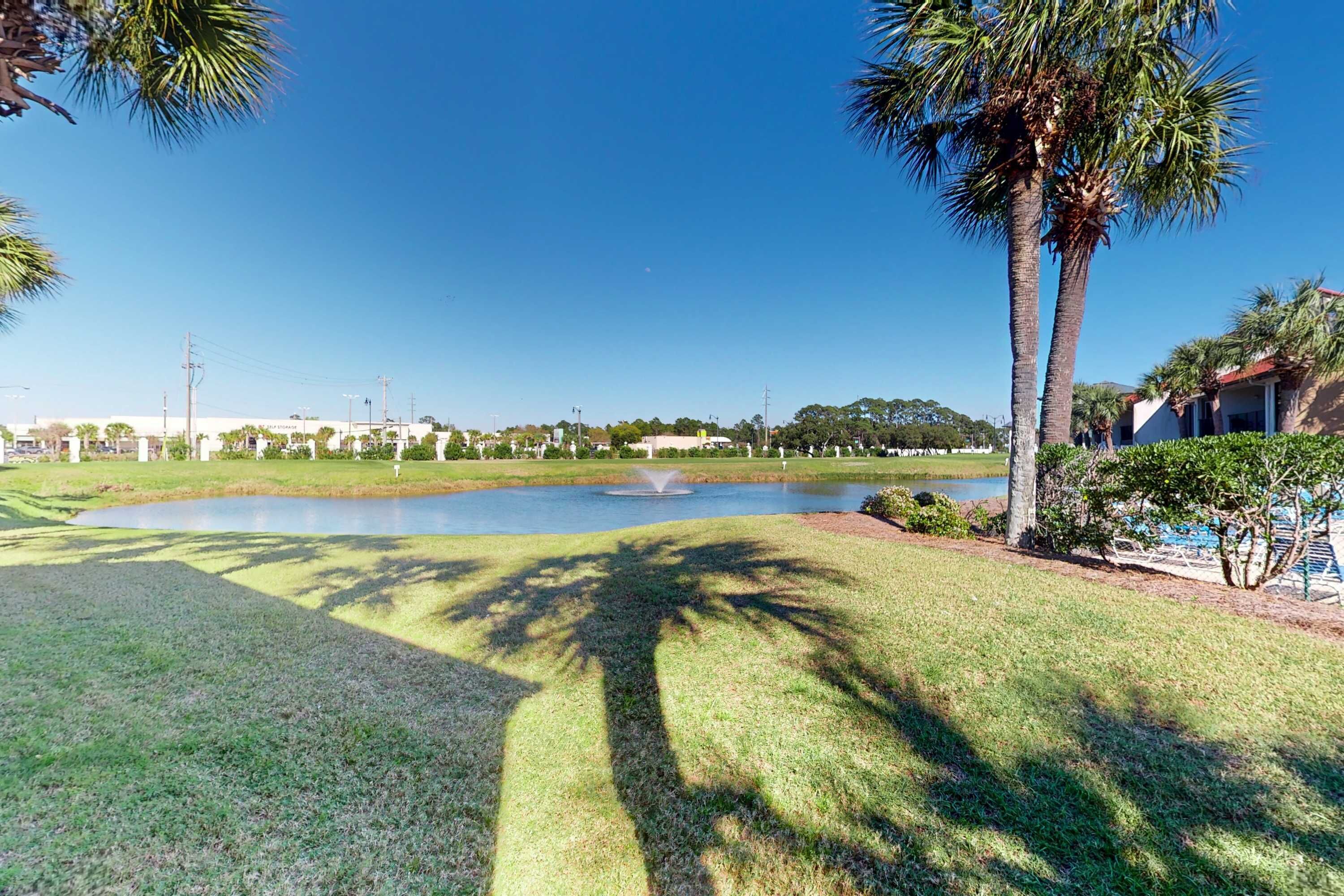 A well-maintained park with a pond, palm trees, and a fountain.