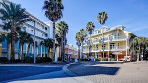 A hotel with a paved courtyard, palm trees, and a sign for 'Drive & Rentals'. - Lakefront, ground-floor condo with pools & hot tubs - walk to the beach (Panama City Beach)