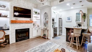 A modern living room with a fireplace, TV, and bar area. - Lakefront, ground-floor condo with pools & hot tubs - walk to the beach (Panama City Beach)