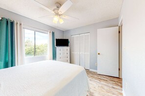 A bedroom with a bed, a ceiling fan, a dresser, a television, and a closet. - Bright retreat near the beach with pool & tennis courts (Panama City Beach)