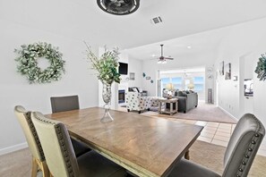 A dining area with a wooden table, upholstered chairs, and a decorative wreath. - Sound-front beauty minutes from beach & pier with private washer&dryer & patio (Navarre)