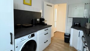 A modern kitchen with a built-in washer, white cabinets, and a wooden floor. - Beautiful Apartment Opposite the Train Station (Kassel)