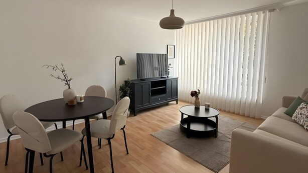 A modern living room with a dining table, sofa, and TV stand. - Beautiful Apartment Opposite the Train Station (Kassel)