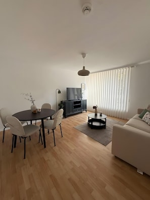 A modern living room with a dining table, sofa, and TV stand. - Beautiful Apartment Opposite the Train Station (Kassel)