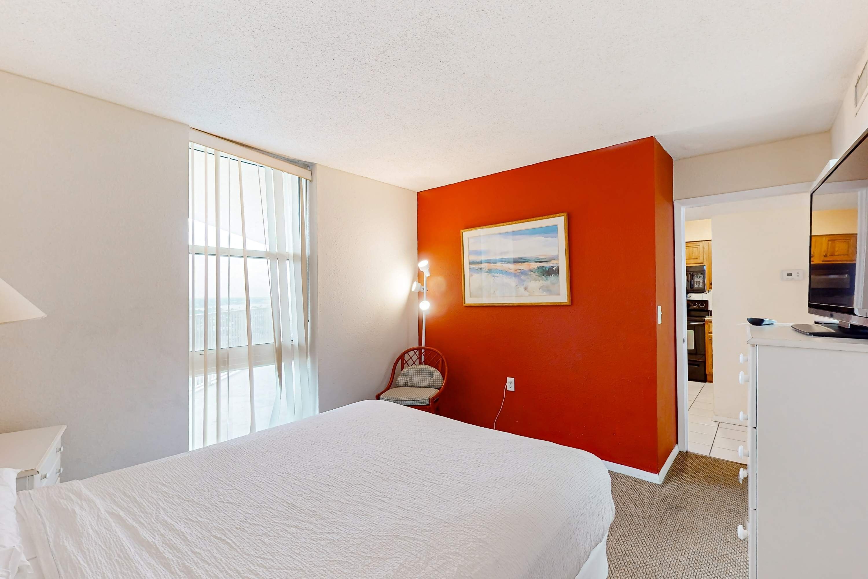 Une chambre d’hôtel avec un grand lit, une chaise, un bureau et un tableau au mur.