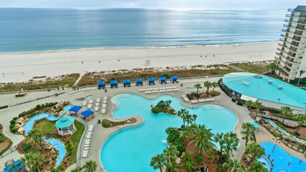 A resort with a large swimming pool, beach access, and a building with multiple balconies. - Terrific condo in beachfront location with pool, central AC & balcony (Panama City Beach)