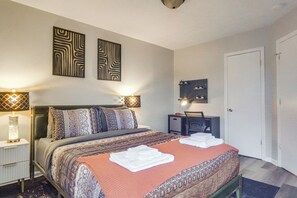 Een keurig opgemaakt hotelkamer met een bed, nachtkastjes, een bureau en een kledingkast.
