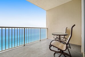 Ein Balkon mit Blick auf den Ozean, einem runden Tisch und zwei Stühlen.