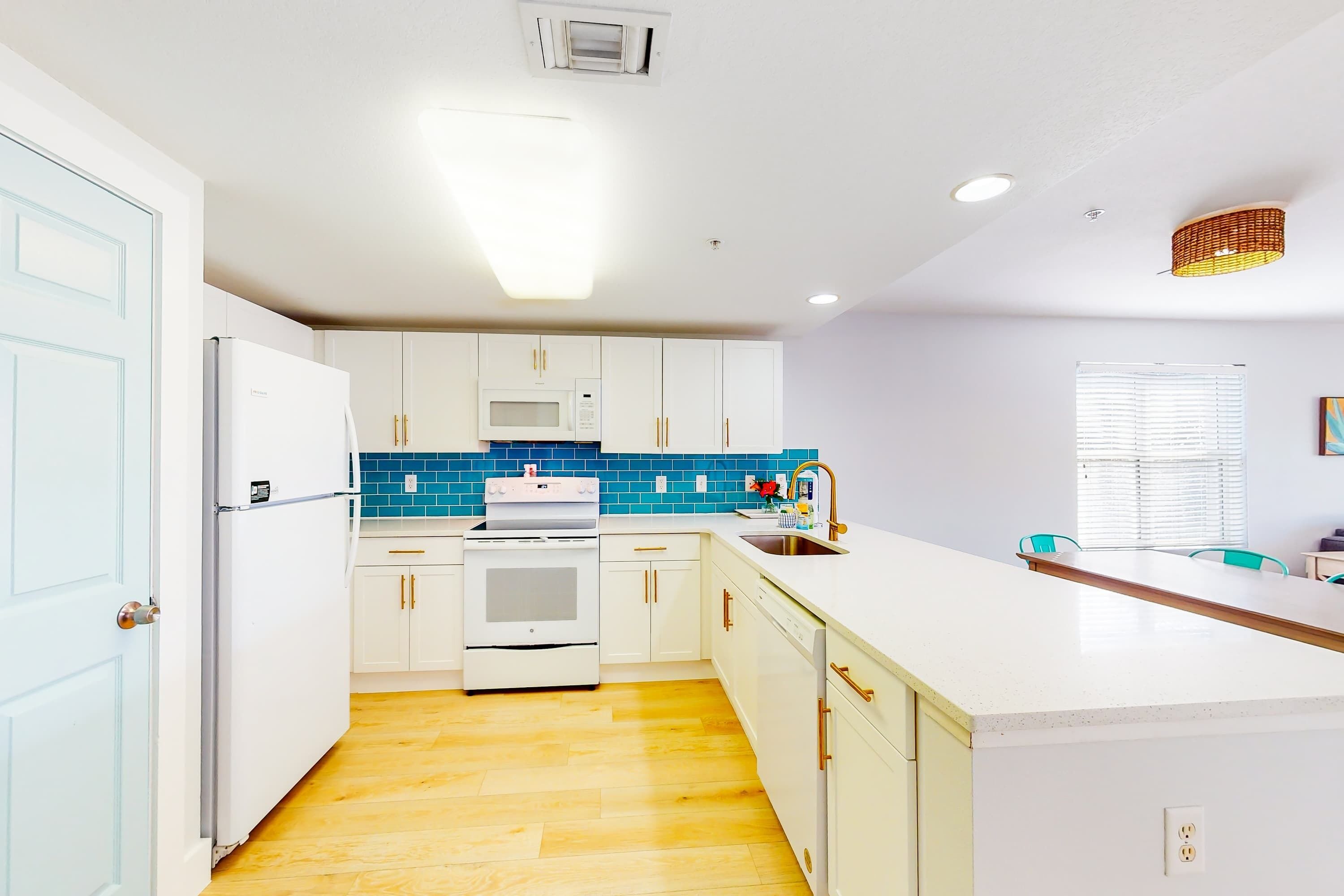 A modern kitchen with white cabinets, a microwave, oven, and a sink.