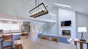 A modern kitchen with a dining area, a staircase, and a fireplace.