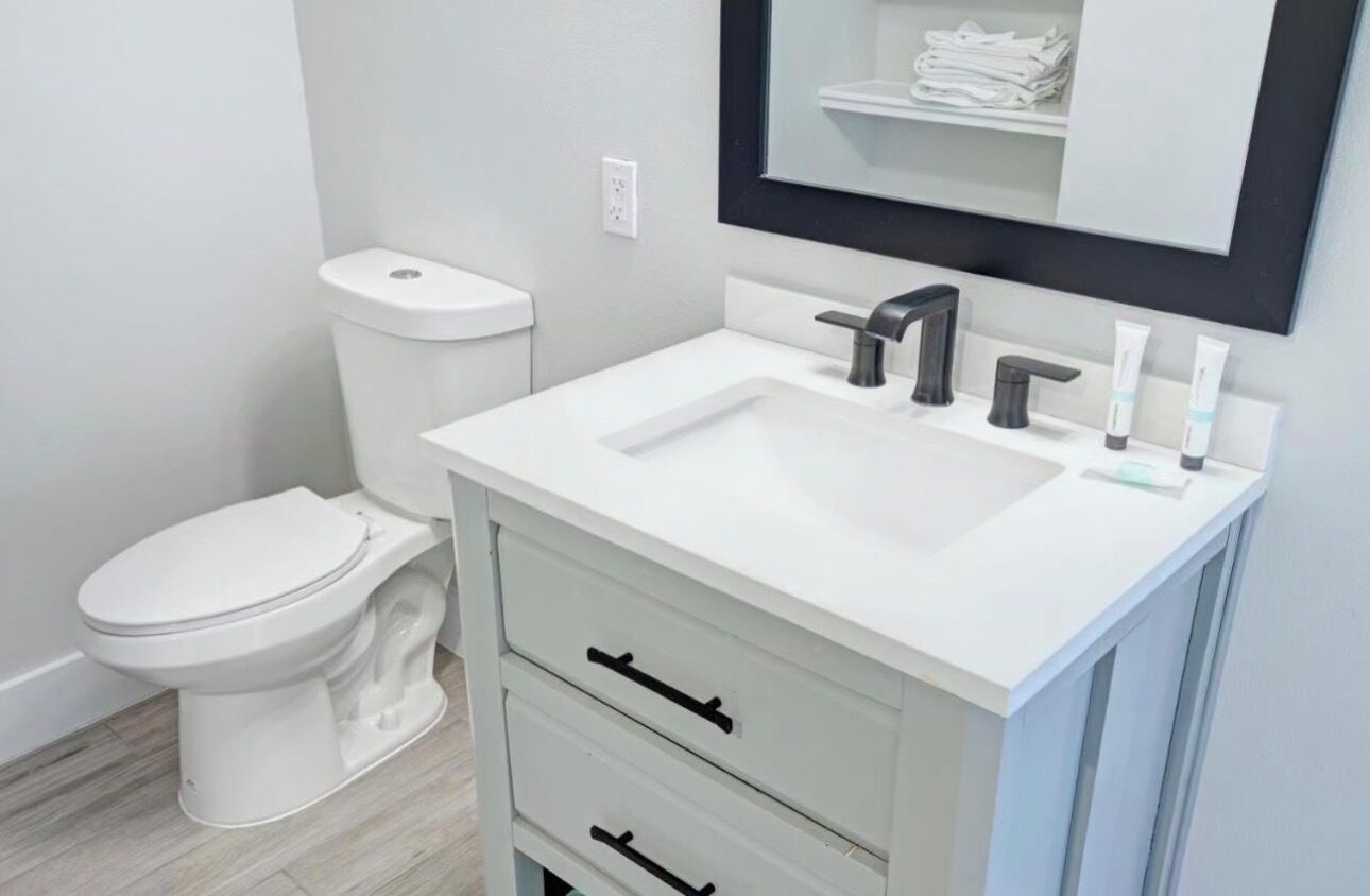 A modern bathroom with a white sink, black faucet, and a toilet.