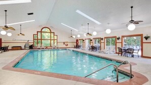 An indoor swimming pool with a clear view of the pool area, ceiling fans, and seating arrangements.
