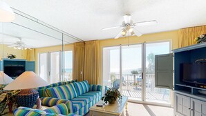 Ein geräumiges Wohnzimmer mit einer großen Couch, einem Fernseher und einem Balkon mit Meerblick.
