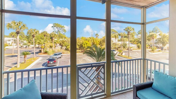 A balcony with a view of a parking lot and palm trees. - Cozy coastal condo with shared pool,  beach access and Wifi (Santa Rosa Beach)