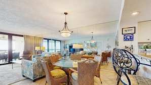 A spacious dining area with a round glass table surrounded by wicker chairs and sofas. - Gulf-view resort condo with pools, hot tubs, balcony, WiFi, W&D, & AC (Miramar Beach)
