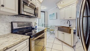 A modern kitchen with white cabinets, stainless steel appliances, and a herringbone tile backsplash.