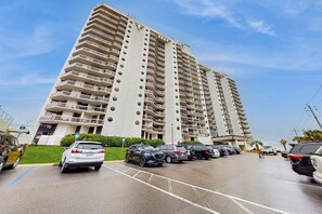 Un immeuble résidentiel à plusieurs étages, doté de balcons et d’un parking situé à l’avant.