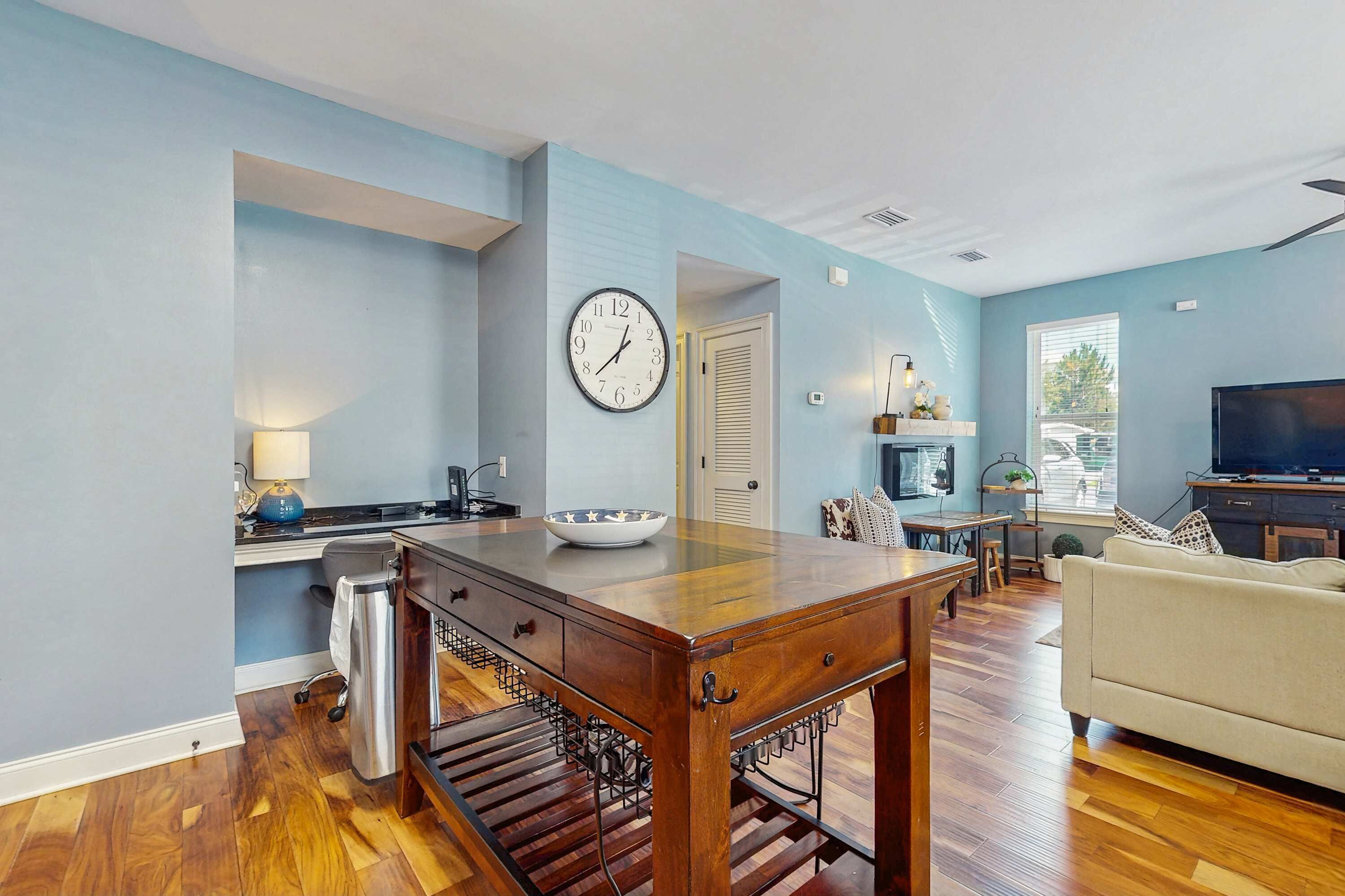 A modern living room with a wooden dining table, a sofa, and a television.