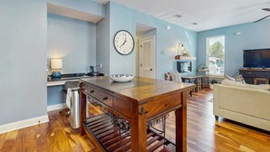 A modern living room with a wooden dining table, a sofa, and a television. - Dog-friendly coastal haven with premium beach perks & resort indulgence (Santa Rosa Beach)